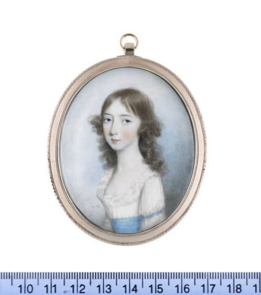 Mary Harrop, wearing white dress with frilled trim, blue sash and matching ribbon at her sleeve, her long locks worn loose.